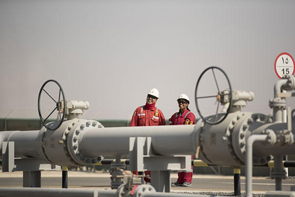 men in front of a pipeline - upstream oil and gas